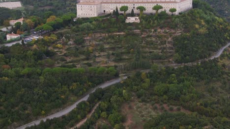 Scenic-aerial-view-of-abbey-of-Montecassino-on-plateau-of-green-rocky-hill-with-Lazio-mountains-in-background,-Italy,-drone-tilt-up