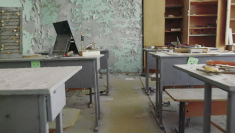 Spaziergang-Durch-Das-Verlassene-Klassenzimmer-Voller-Müll-Und-Rostiger-Schreibtisch-Mit-Leerem-Schrank-In-Der-Von-Tschernobyl-Betroffenen-Schule,-Ukraineweit-Rollend