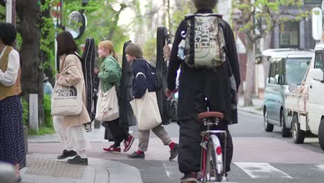 Músicos-Japoneses-Caminando-Y-Cruzando-La-Calle-En-Kyoto,-Japón-Durante-El-Día