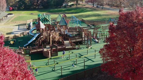 Aerial-reveal-of-children,-moms,-dads-on-zip-line-at-community-park-playground