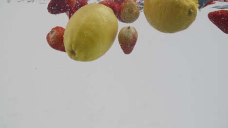 Ganze-Erdbeeren-Und-Zitronen,-Die-Im-Wasser-Planschen