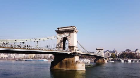 Statische-Aufnahme-Der-Budapester-Kettenbrücke-Mit-Menschen,-Die-Darauf-Laufen,-Und-Booten-In-Der-Donau