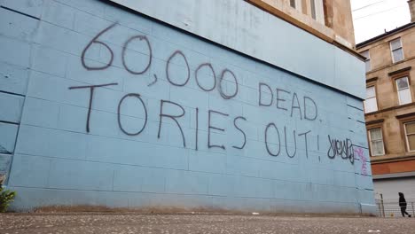 A-low-angle,-wide-shot-of-an-anti--Conservative-graffiti-on-a-corner-shop-wall