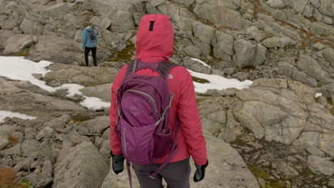 Two-Women-Hiking-Over-Rocky-and-Snowy-Terrain-on-a-Cold,-Overcast-Day-in-Norway,-Slow-Motion