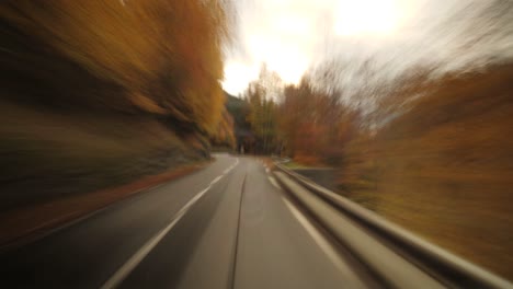 A-fast-Hyperlapse-of-a-camping-van-driving-on-a-mountain-road-in-the-French-Alps-during-autumn,-with-golden-trees-and-motion-blur