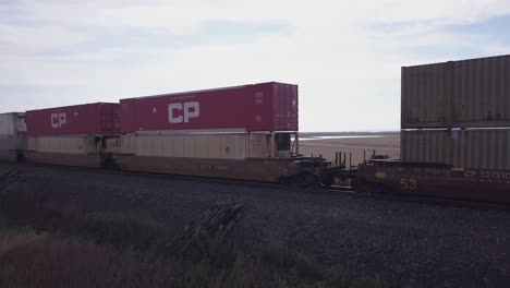 Stacked-CP-cargo-containers-on-freight-train,-panning-right-to-left