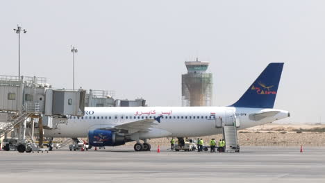 Avión-De-Pasajeros-Estacionado-En-El-Fondo-De-La-Torre-De-Control-Del-Aeropuerto-De-Puerta