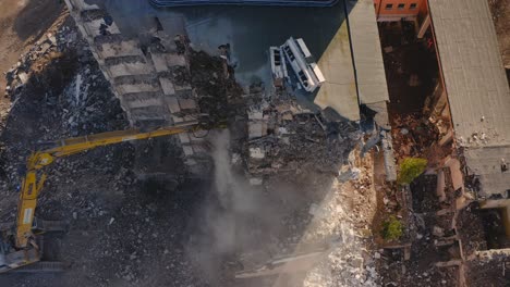 Aerial-drone-view-of-claw-Excavator-demolishing-a-concrete-building-or-apartment