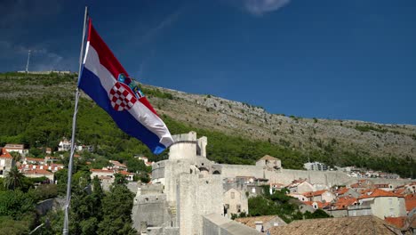 Aufnahme-Der-Kroatischen-Flagge,-Die-An-Der-Mauer-In-Der-Altstadt-Von-Dubrovnik-Weht,-Mit-Dem-Berg-SRD-Im-Hintergrund