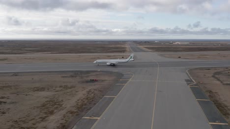 Business-jet-using-taxiway-to-enter-runway-of-remote-airport-in-Iceland,-aerial