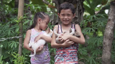 Entzückende-Kleine-Kinder-Lächeln-Vor-Der-Kamera-Und-Halten-Zwei-Süße-Welpen-Auf-Den-Philippinen-–-Extremes-Glück-–-Mittlere-Aufnahme