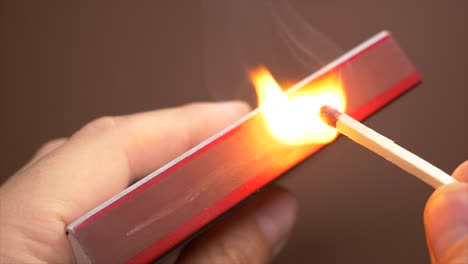 Slow-motion-shot-of-male-hand-igniting-match-on-matchbox