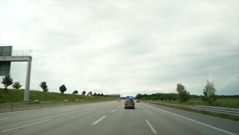POV-front-view-through-windshield-during-holiday-drive-to-Austria-on-german-freeway-in-Bavaria