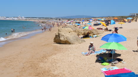 Tourists-on-beach-towels-and-under-parasol-umbrellas-on-Portuguese-beach