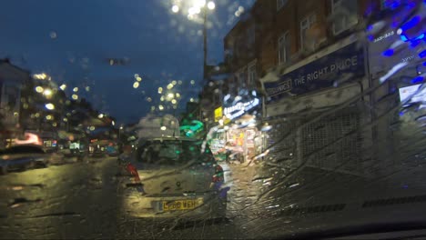Regen-Fällt-Nachts-Auf-Die-Windschutzscheibe-Eines-Geparkten-Autos,-Während-Autos-Vorbeifahren