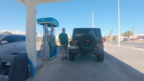 Man-filling-the-gas-tank-of-his-Jeep-at-fuel-station-on-a-sunny-morning