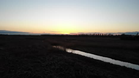 Ruhiger-Fluss-Zwischen-Feldern-Bei-Sonnenuntergang-In-Der-Wintersaison
