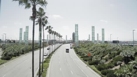 Circular-glass-column-sculpture-with-two-lane-road-with-palm-trees-near-the-Mathare-area,-Aerial-orbit-around-shot