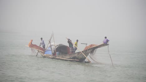 Ein-Bangladeschischer-Fischer-Breitet-Netze-Im-Fluss-Aus-Und-Versucht-Mit-Aller-Kraft,-Das-Boot-Zu-Kontrollieren