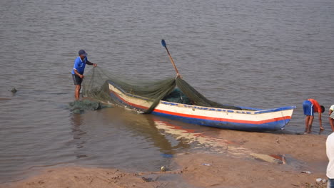 Un-Pescador-Indio-Preparando-Y-Limpiando-Su-Red-De-Pesca-Y-Un-Pequeño-Bote-De-Pesca-Cerca-De-Una-Orilla-Antes-De-Ir-Al-Mar-Para-Pescar-Fondo-De-Video-En-Prores-422-Hq