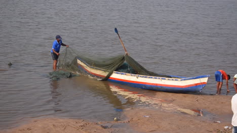 Ein-Indischer-Fischer-Bereitet-Und-Reinigt-Sein-Fischernetz-Und-Sein-Kleines-Fischerboot-In-Küstennähe,-Bevor-Er-Zum-Angeln-Ins-Meer-Geht.-Videohintergrund-In-Prores-422-HQ