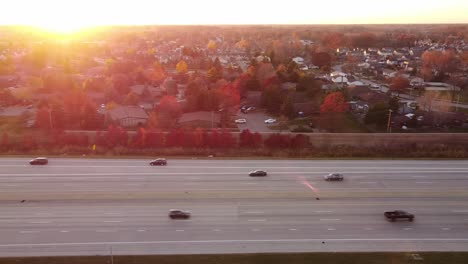 Autos-Und-Lastwagen-Fahren-Auf-Der-Autobahn-I-75,-Die-Wyandotte-Und-Brownstown-In-Michigan-Verbindet,-Mit-Bunten-Bäumen-Bei-Einem-Herbstsonnenaufgang---Luftaufnahme