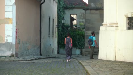 Couple-Walking-In-Alleyway-Surrounded-With-Old-Buildings-In-Bratislava,-Slovakia