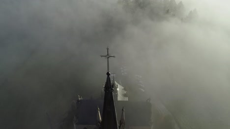 Heavenly-scene-of-neo-Gothic-church-surrounded-by-eerie-mist-in-Poland,-aerial