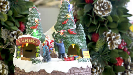Niedliches-Beleuchtetes-Schneedorf-Spielzeug-Mit-Zug-In-Bewegung-Auf-Weihnachtlichem-Hintergrund