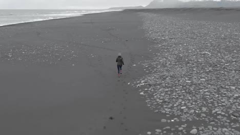 Rising-Follow-Shot-of-Woman-Running-Along-a-Beach