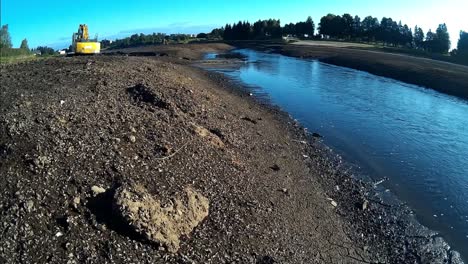 Piedra-En-Forma-De-Corazón-Y-Excavadora-Amarilla-En-El-Lodo-Y-Lodo-Del-Río-Drenado