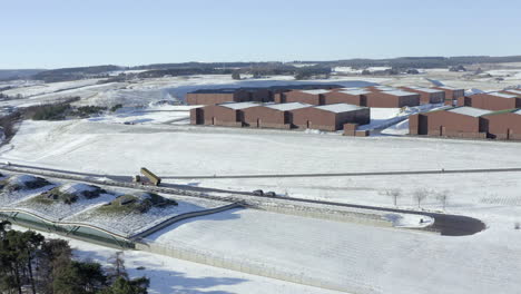 Aerial-view-of-the-Macallan-whisky-distillery-surrounded-by-snow-on-a-sunny-winters-day,-Moray,-Scotland---tracking-right-to-left