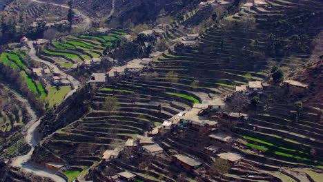 A-village-houses-with-beautiful-scenes-of-mountains-and-river-aerial-view,-as-well-as-charmingly-crafted-greenery-with-a-road-where-traffic-is-moving