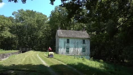 Mature-woman-bikes-past-an-old-building-on-the-C-O-Canal-National-Historic-Park-near-Harpers-Ferry,-West-Virginia