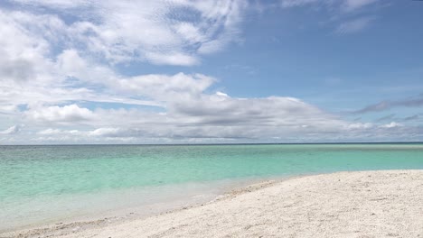 Wunderschönes-Blaues-Meerwasser-Mit-Wellen,-Die-Sanft-An-Einem-Weißen-Tropischen-Sandstrand-Unter-Einem-Blauen-Himmel-Mit-Flauschigen-Wolken-Auf-Den-Philippinen-An-Land-Spülen