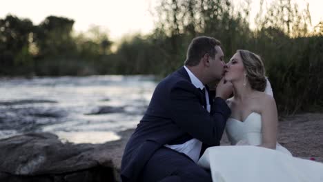 This-beautiful-couple-moves-in-for-a-kiss-whilst-sitting-on-the-river-bank-after-they-got-married-moments-before
