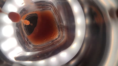 Extreme-slow-motion-shot-of-red-thick-fruit-juice-or-cocktail-poured-into-a-transparent-and-reflective-glass-surface
