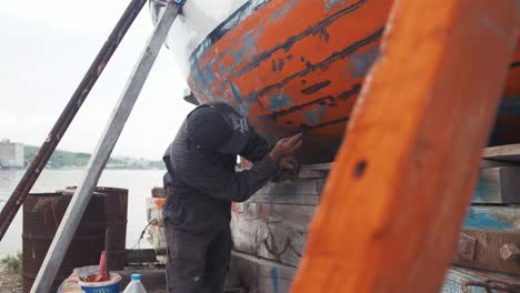 Fischer-Repariert-Fischerboot-Mit-Wasserdichtem-Dichtmittel-In-Zeitlupe