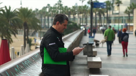 Business-man-checking-his-phone-in-Passeig-Marítim-de-la-Barceloneta,-Barcelona-Spain