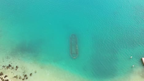 Aerial-view-of-rusty-shipwreck-on-seafloor-in-turquoise-ocean