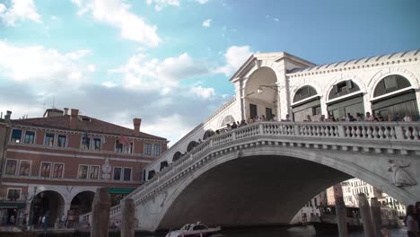 Tourists-gather-at-the-Rialto-Bridge-while-boats-the-Gondolas-travel-below-in-Venice