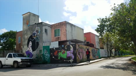 Joven-Caminando-Con-Mochila-Roja-Lejos-De-La-Cámara-Pasando-Graffiti-En-Un-Centro-Urbano-De-México