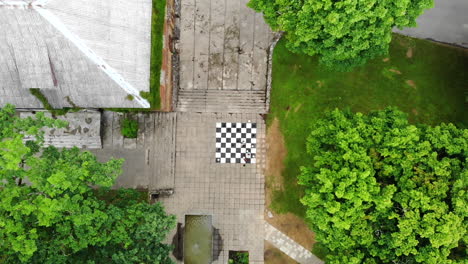 Luftaufnahme:-Weitwinkel-Drohne-Hebt-Sich-über-Kinder,-Die-Schach-Spielen,-Das-Auf-Die-Steine-Auf-Dem-Boden-Gemalt-Ist