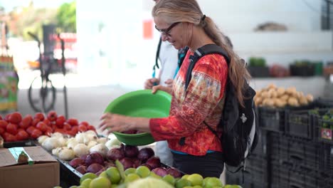Mujer-Madura-Eligiendo-Cebollas-En-Un-Mercado-De-Frutas-Y-Verduras-Al-Aire-Libre
