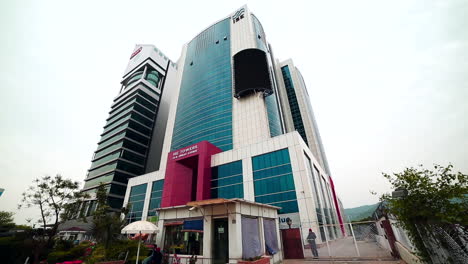 Low-angle-panning-view-of-a-latest-building,-The-building-has-blue-coloured-glass-around-it,-a-digital-SMD-led-display-video-wall-screen-is-fixed-on-the-building