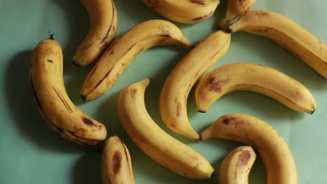 Una-Toma-Macro-De-Plátanos-Orgánicos-Amarillos-Maduros-Girando-Contra-Un-Fondo-Verde