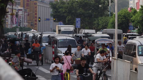 Cars,-motorbikes-and-rickshaw-heavy-loaded-with-textile-rolls-driving-in-the-street-of-textile-market-area-in-Guangzhou,-China