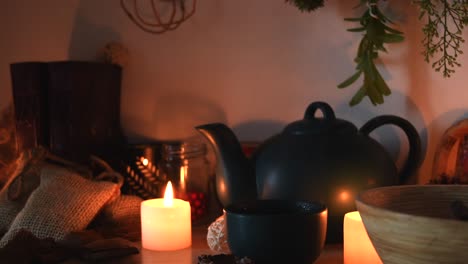 Relaxing-background-detail-shot-of-an-herbal-tea-shop,-with-candles-with-flickering-flames,-a-tea-pot,-a-cup-with-steam-coming-out,-herbs-hanging,-books,-and-some-dust-flying-around