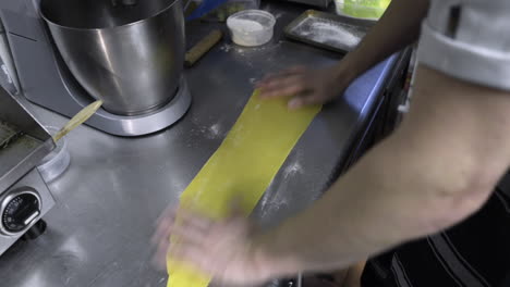 Pasta-being-floured-and-brushed-off-by-a-chef-on-a-kitchen-counter