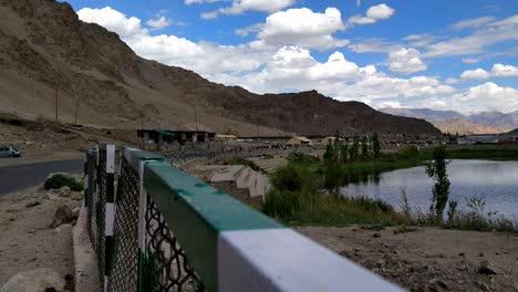 the-clean-and-serene-roads-of-leh-with-lake-blue-sky-white-clouds-and-car-and-vehicle-moving-on-the-roads-in-between-mountains